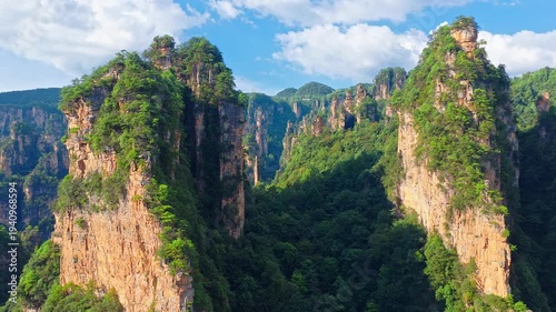 Breathtaking quartz sandstone pillars in Zhangjiajie, Hunan, China, showing dramatic mountain landscape and lush vegetation under blue sky for nature and travel concept.