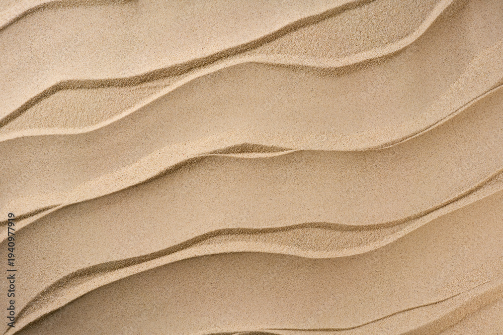 Fototapeta premium Wavy and dry sand, close up. Beach sand texture. sandy background with golden and white grains.