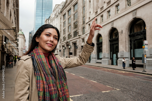 Photography Woman hailing taxi cab on a city street in london
