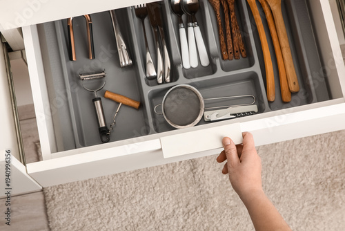 Photos Woman opening drawer of utensils in kitchen, top view