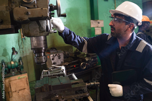 Bild auf Leinwand Multi-ethnic team of professional engineers and technicians operating heavy machinery and using digital tablets for production control in a modern factory