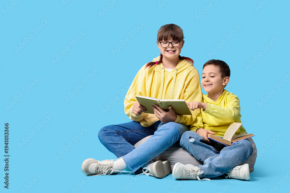 Naklejka premium Cute girl with her brother reading book in beanbag on blue background