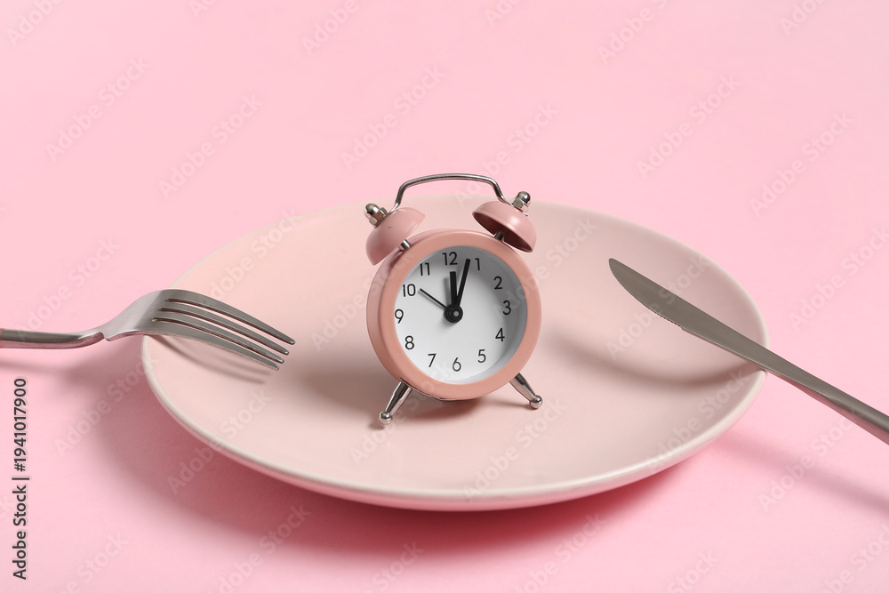 Fototapeta premium Table setting with alarm clock on pink background. Intermittent fasting concept