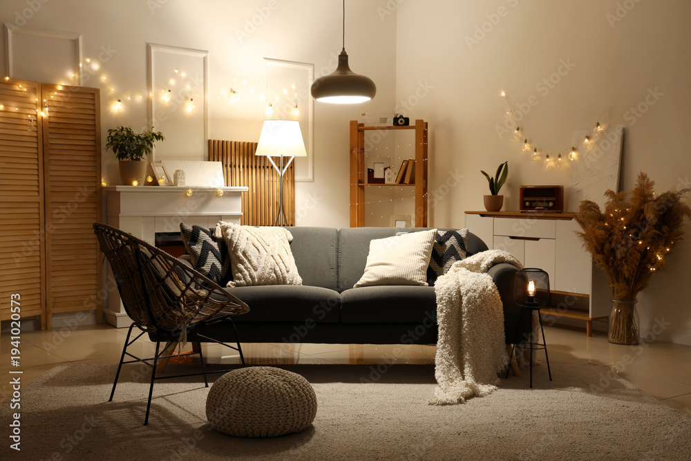 Fototapeta premium Interior of living room with sofa, armchair and glowing lights in evening