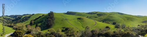 Wide panoramic landscape of rolling green hills under a clear blue sky. Garin Regional Park, Alameda County, California.