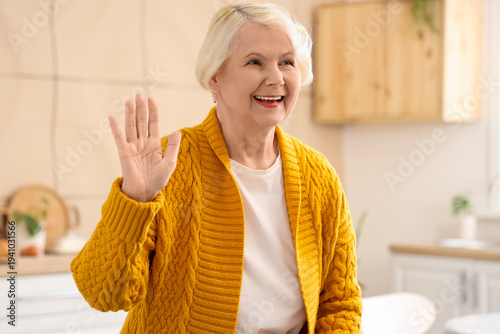 Senior woman waving hand in...