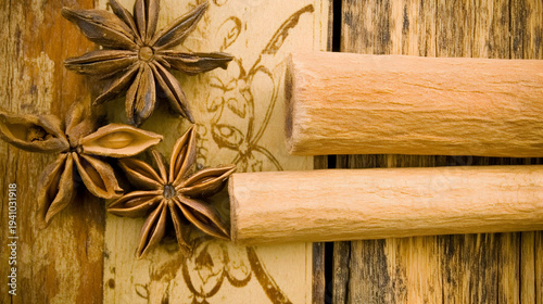 Cinnamon sticks and star anise on wooden background with floral design