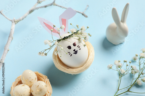 Nests of cute painted Easter eggs with drawn face, branch and flowers on blue background