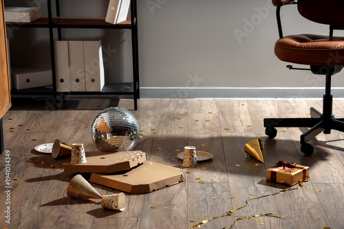 After party mess with disco ball and pizza boxes on wooden floor in office