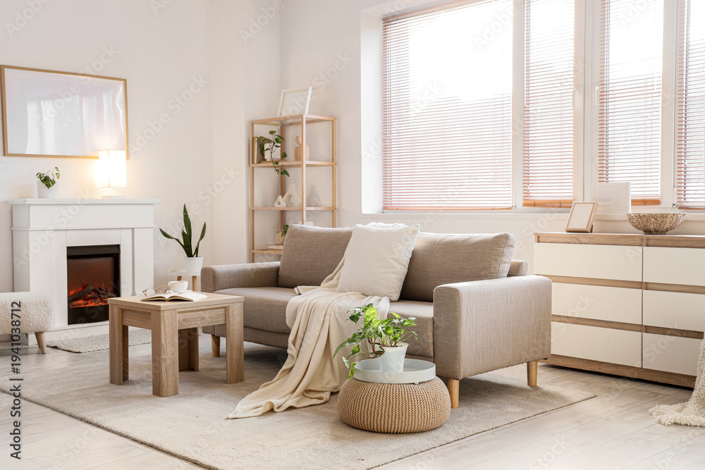 Obraz premium Interior of light living room with grey sofa, coffee table and fireplace