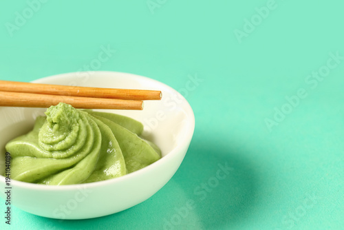 Canvas Print Bowl with wasabi paste and chopsticks on turquoise background, closeup