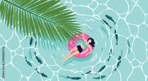 Top down view of a young woman relaxing on a pink inflatable ring in clear turquoise water surrounded by a school of fish and a green palm leaf.