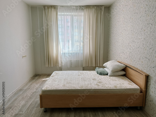 Tableau sur toile Bedroom with wooden bed and light curtains. Small empty room