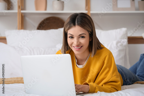 Smiling young woman using l...