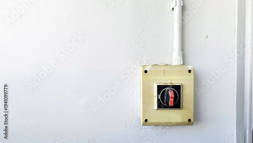 Foto Power Switch on the wall: A close-up shot of a power switch mounted on a simple wall, highlighting its crucial role in controlling electrical systems