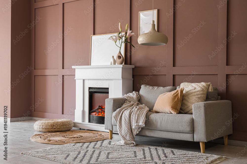 Fototapeta premium Interior of cozy living room with grey sofa, wicker pouf and stylish fireplace