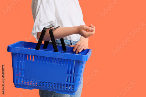 Foto Woman with blue shopping basket on orange background