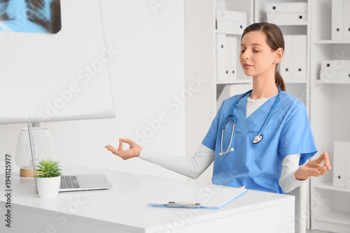Female doctor meditating at table in clinic