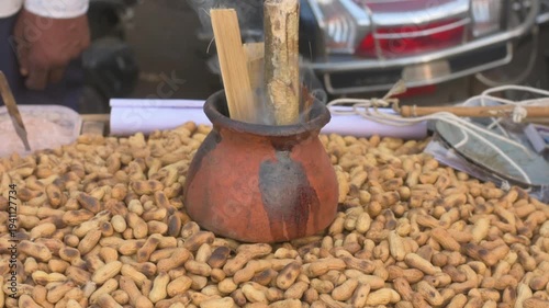 Street vendor peanut stall with smoking clay charcoal pot and roasted peanuts in shells