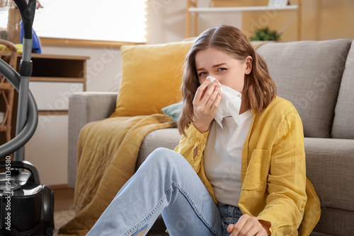 Young woman suffering from dust allergy while cleaning flat