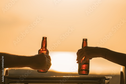 Konstfotografi beer in the hand of a couple watching the sunset