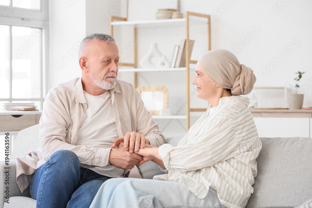 Obraz premium Mature woman after chemotherapy with her husband holding hands on sofa at home