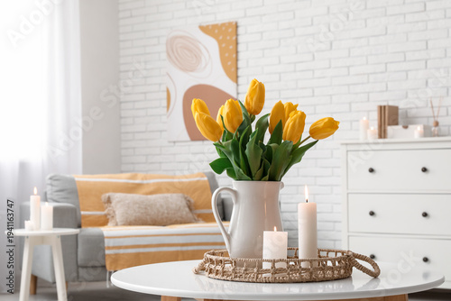 Tray with burning candles and tulip flowers in vase on table in interior of living room, closeup