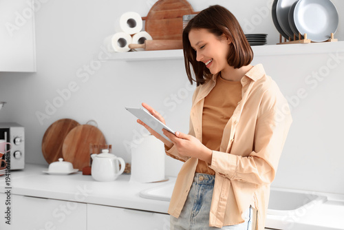 Young woman using tablet computer in kitchen