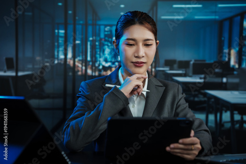 Focused businesswoman using tablet in modern office at night