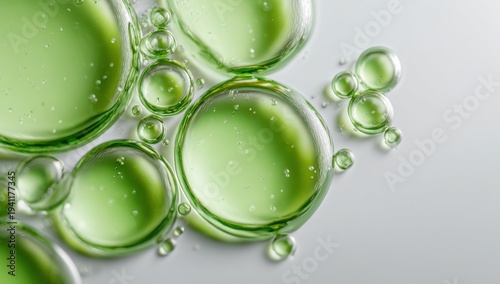 A close-up view of green bubbles on a light background, showcasing their translucent textures and reflections.