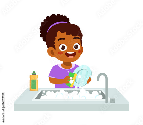 Happy Black girl washing dishes with sponge and soap bubbles in kitchen sink smiling cheerfully