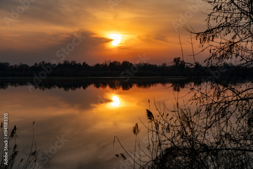 Fotografia A serene and beautiful sunset over a tranquil lake, featuring the sun in a distinct heart shape amidst warm, glowing clouds