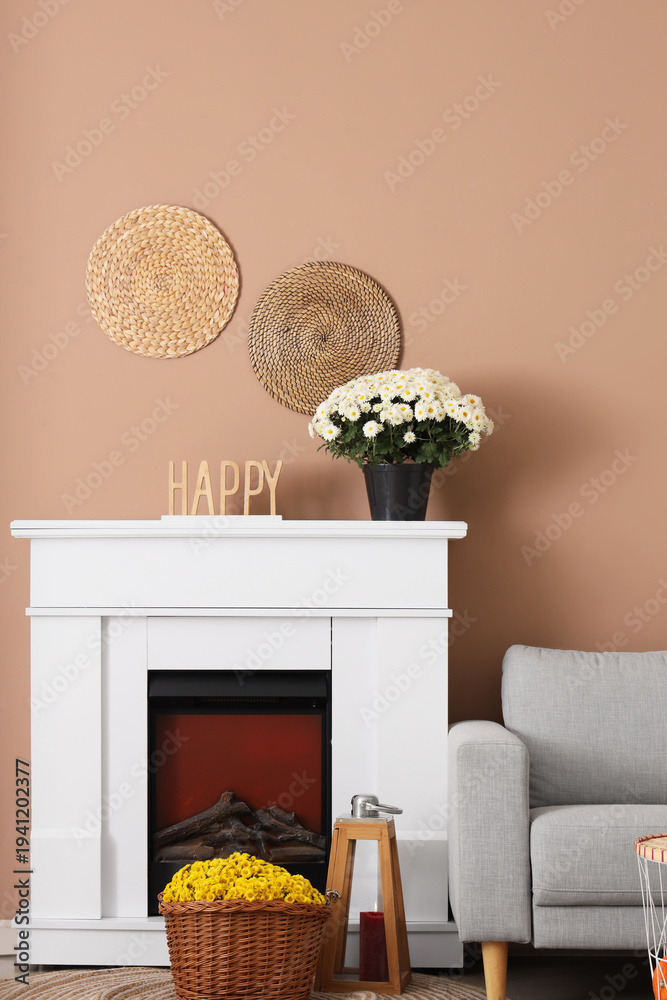 Obraz premium Fireplace and chrysanthemums near beige wall in room
