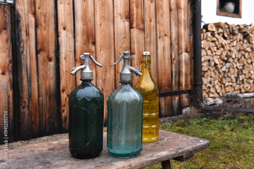 Foto Vintage glass soda siphons and yellow bottle on rustic wooden bench
