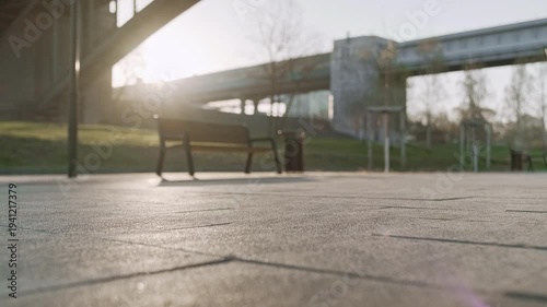 Sportsman in athletic clothing fastening his running shoes beneath a bridge at sunrise. The image captures preparation for a morning run, emphasizing urban fitness, motivation, and active lifestyle.