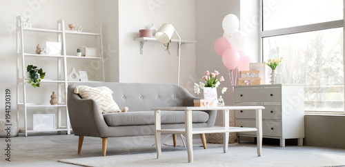 Interior of light living room decorated for Mother's Day with sofa, table and balloons