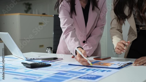 Business documents on office table with smart phone and calculator digital tablet and graph business with social network diagram and two colleagues discussing data working in the office.