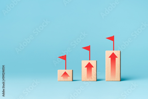 Arrow up on wooden block with flag target. Ladder of success in business growth concept.