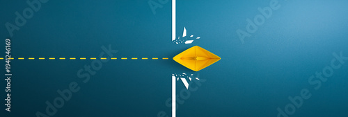 Yellow paper ship breaking through obstacle on blue background, Concept of overcoming barriers, goal, target