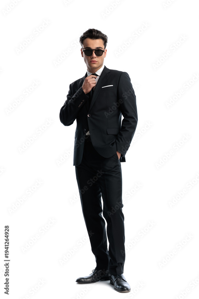 Obraz premium Confident man with hand in pocket adjusting tie