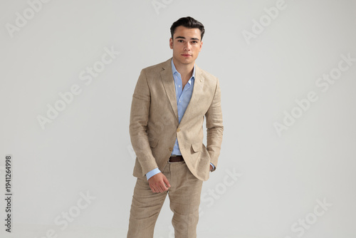 Handsome man posing in beige suit with hand in pocket