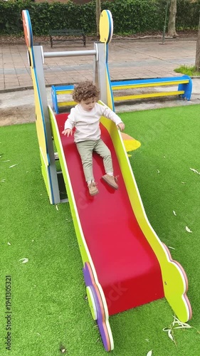 Niño jugando solo en tobogán de parque infantil moderno y seguro