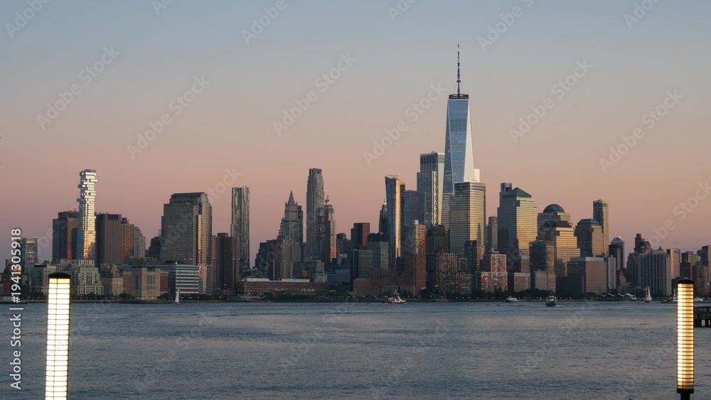 Obraz premium New York City Manhattan Downtown Financial District skyline, World Trade Center tower skyscraper from New Jersey, Hoboken pier, United States. River waterfront urban cityscape, evening dusk twilight.