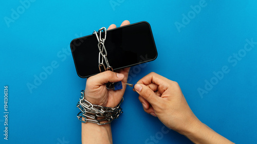 Photography Hands chained to a smartphone being unlocked with a key