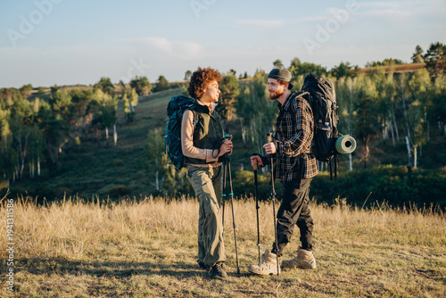 Photography Romantic mixed race couple with Nordic walking sticks stands on sunset hill