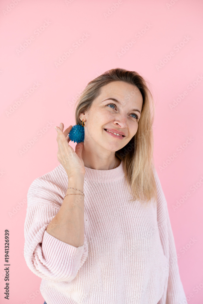 Naklejka premium Blonde woman with blue massage ball in front of pink background