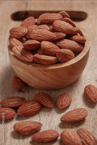 Almonds placed in a wooden cup and on a natural wood plate, highlighting simple organic textures.