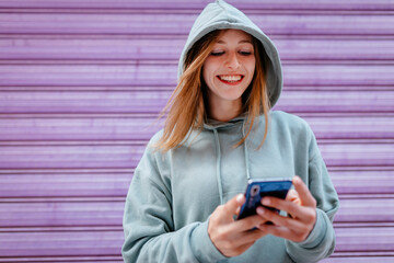 Portrait of young blonde woman with green hoodie and purple background