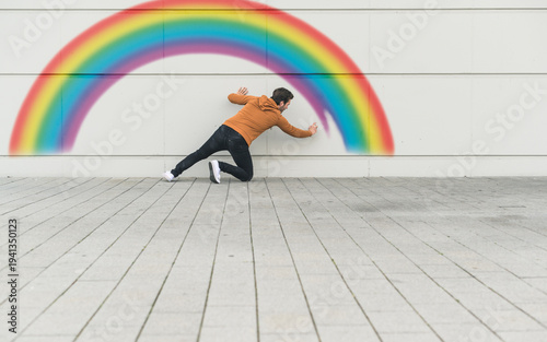 Digital composite of young man painting a rainbow at a wall