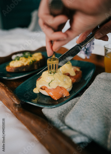 Photography Hand cuts into creamy eggs benedict on salmon